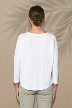 Ein weißes Langarmshirt für Damen aus umweltfreundlicher Bio-Baumwolle. Das Shirt hat eine lockere Passform und einen Frontdruck mit einem Frauen-, Halbmond- und Wellendesign. Der Stoff hat eine weiche Textur und bietet dem Träger ein angenehmes Tragegefühl. Das Produkt ist umweltverträglich und fördert einen bewussten Konsum.